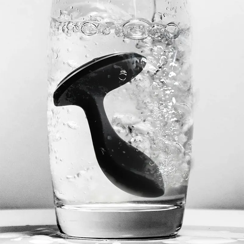 BoomPro electric shock butt plug submerged in a glass of water, showcasing its IPX7 waterproof rating for safe use in wet environments like showers or baths.