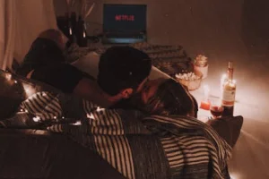 A couple laughing together during a romantic setup with dim lights, preparing to use a vibrator.